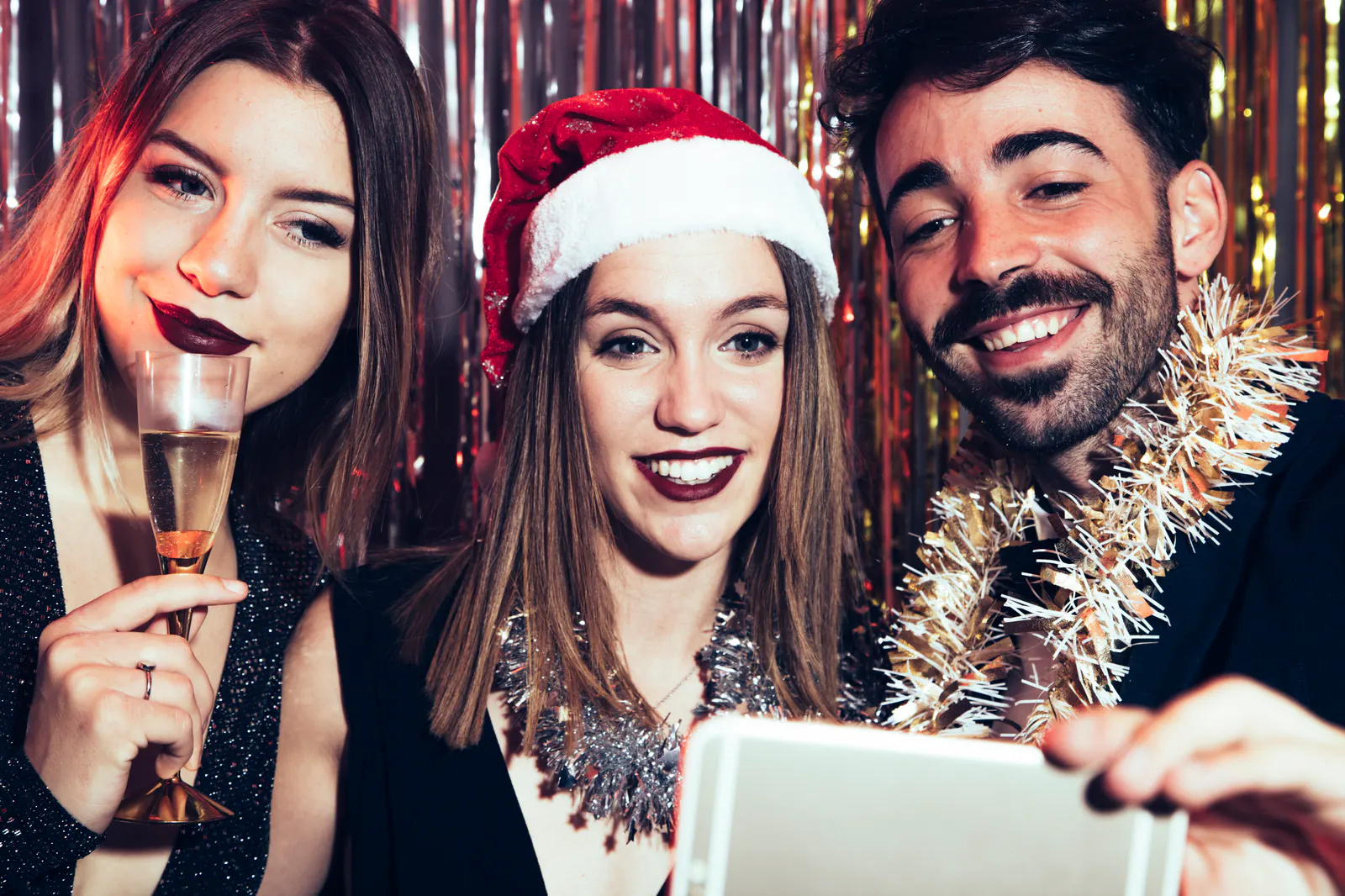 Drei Gäste machen bei einer Weihnachtsfeier ein Selfie